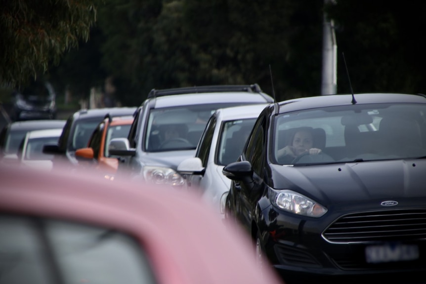 A row of cars are banked up in a residential street.