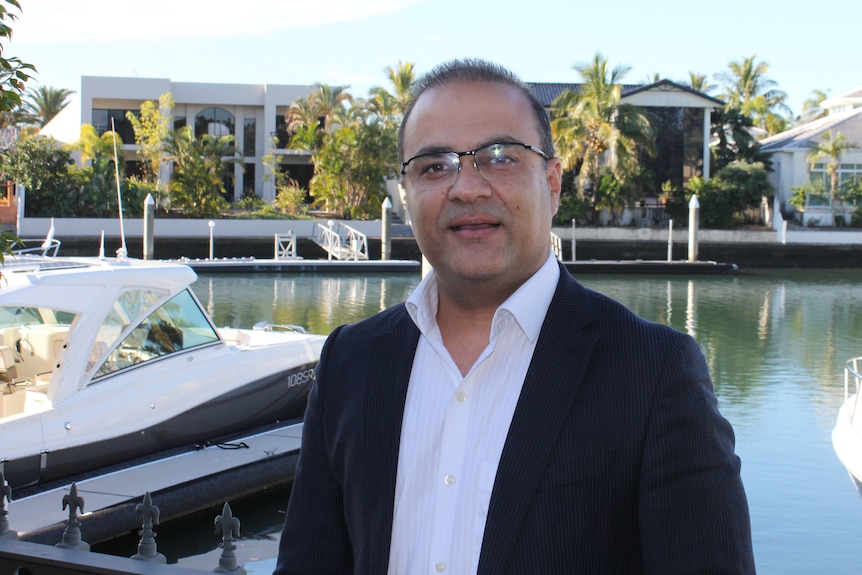 Real Estate owner Ali Mian standing in front of mansions and luxury boats moored at Sovereign Islands gated community