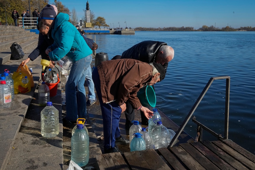 people standing by a river with large plastic bottles