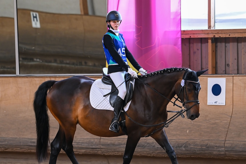 A woman rides a horse in an arena.
