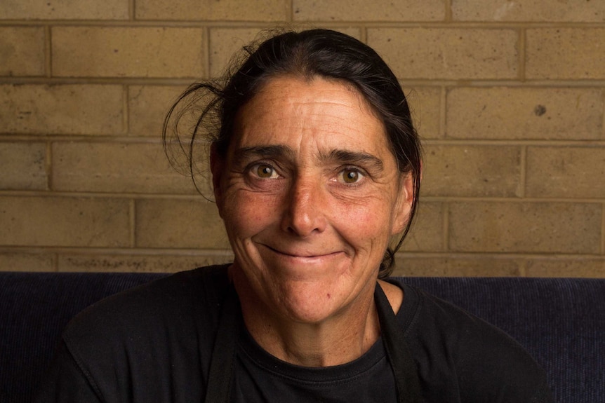 Donna Abbott sits in front of a wall.