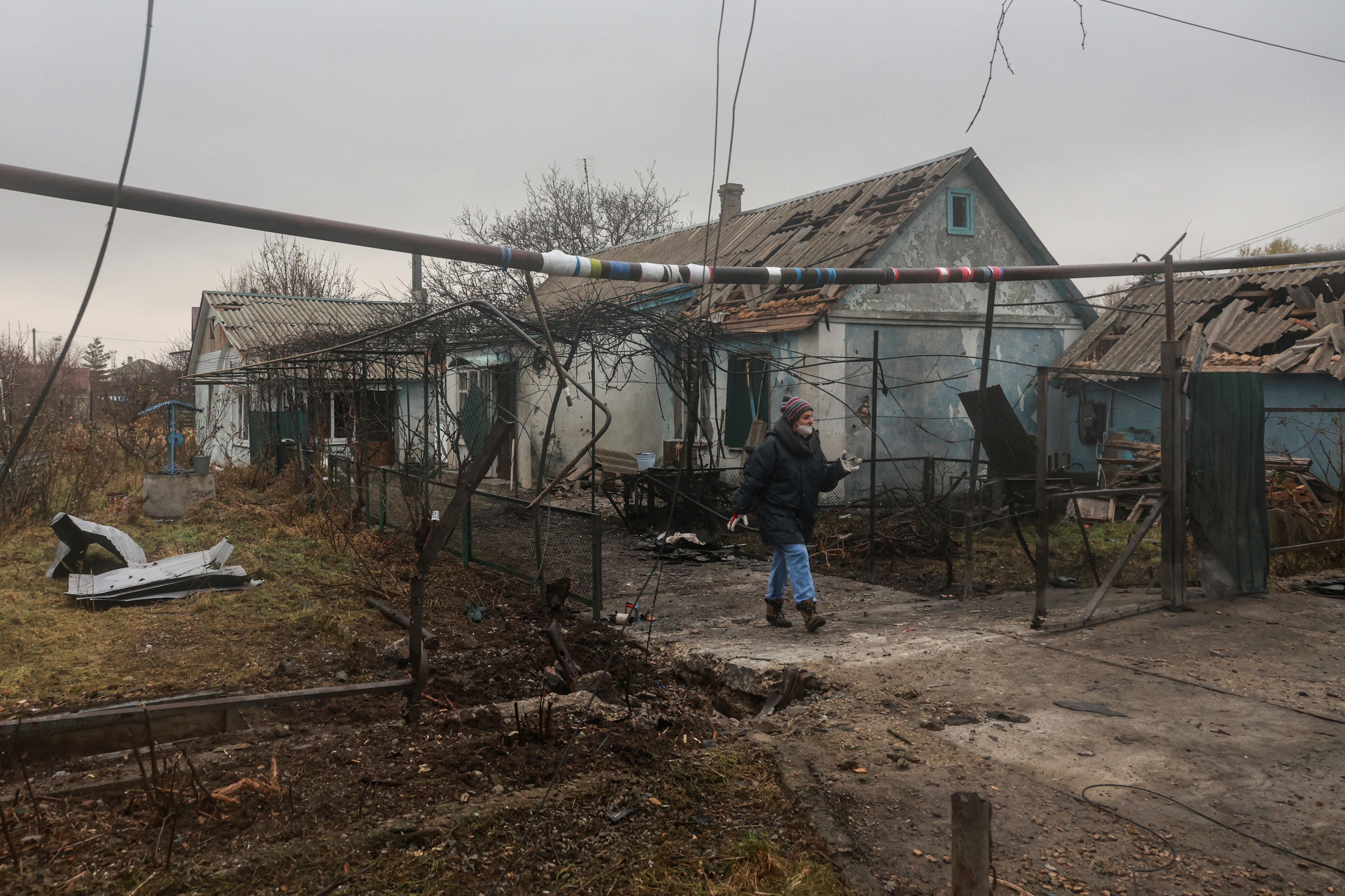 A person walked passed a destroyed house. 