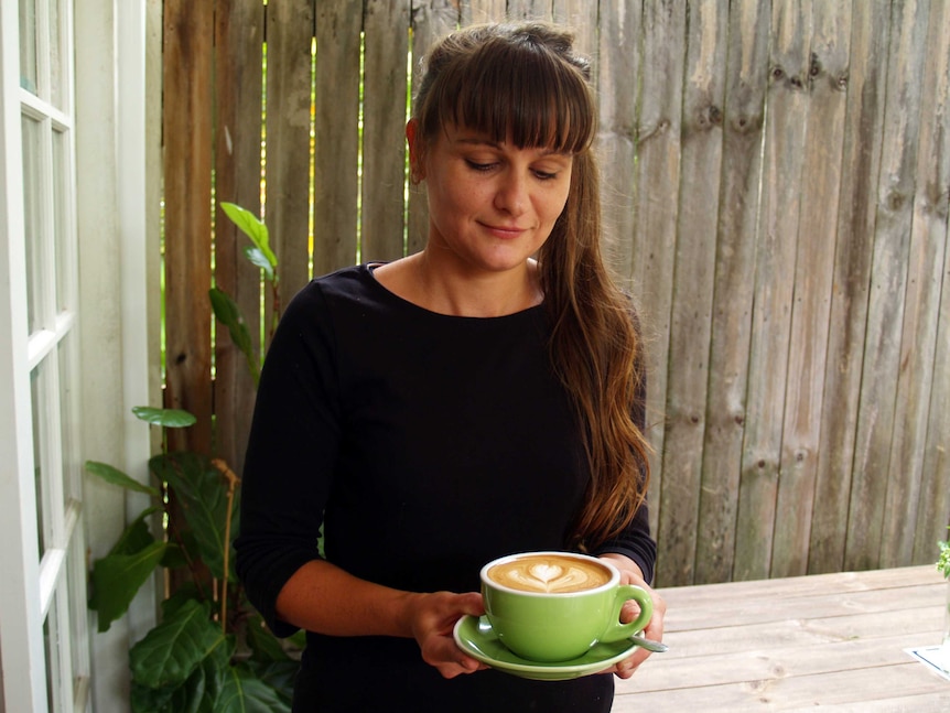 Barista Libbi Rose Seymour holding up a freshly brew coffee cup at Green Lane plantation.