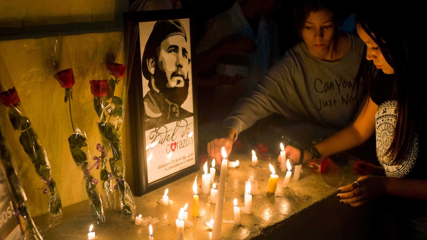 Students place candles and roses around an image of the late Cuban leader Fidel Castro.