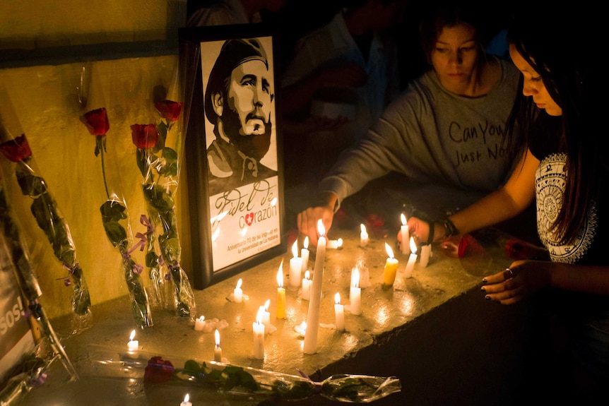 Students place candles and roses around an image of the late Cuban leader Fidel Castro.