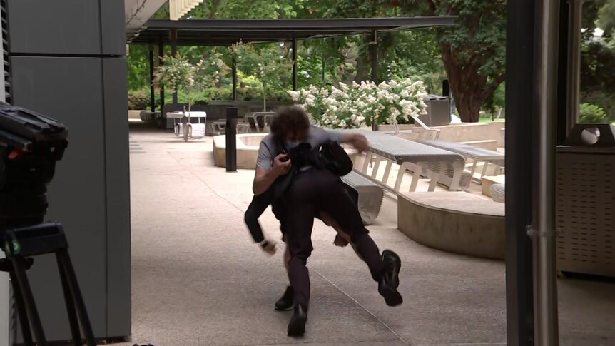 A security officer tackles a protester to the ground in Adelaide.