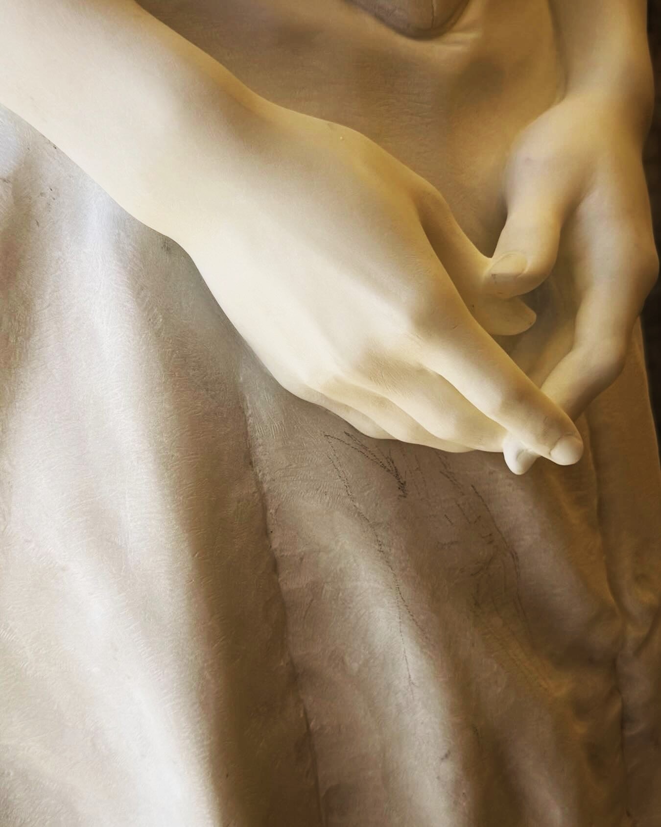 Primer plano de las manos de una escultura de mármol.