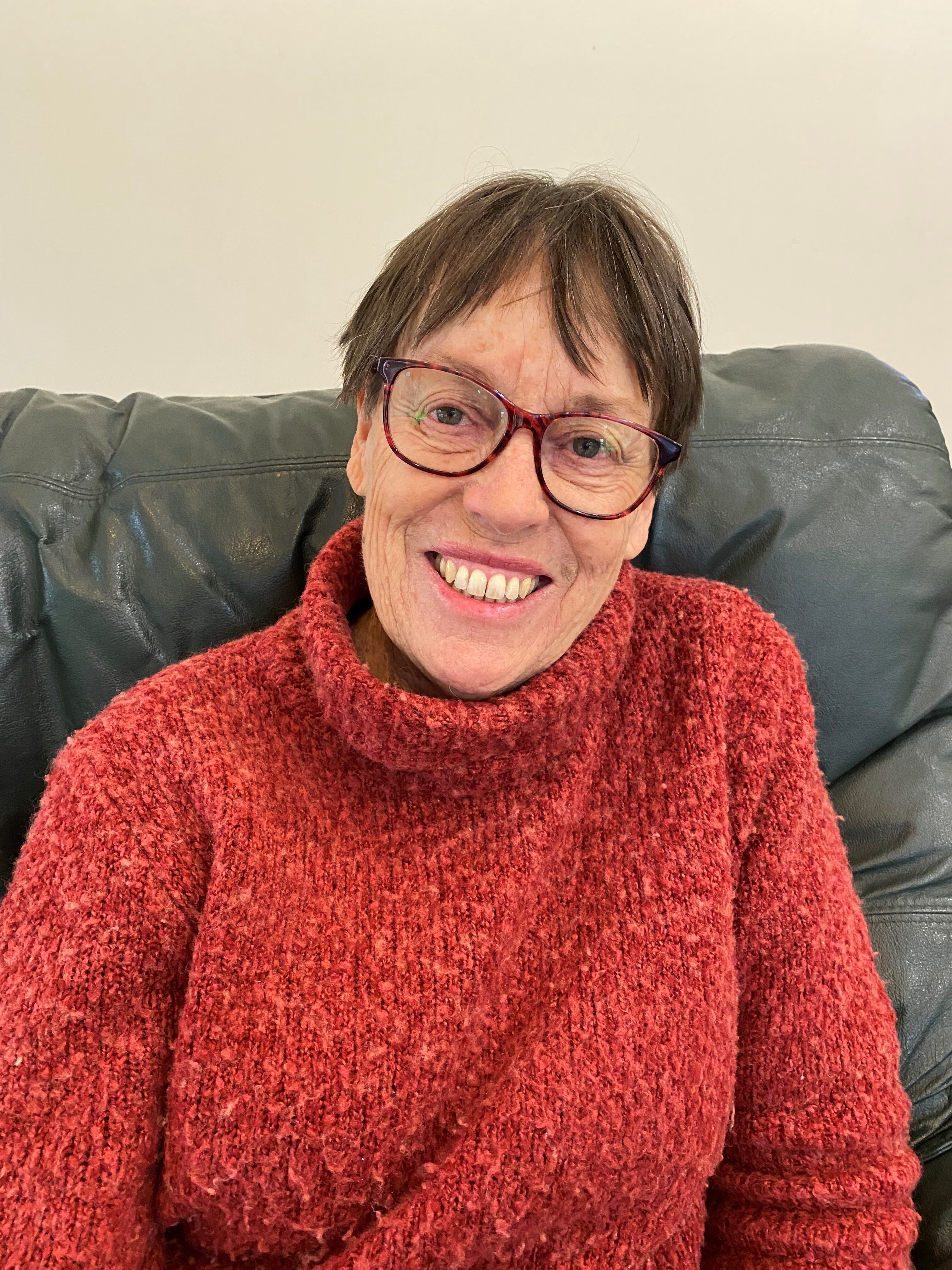 Woman in red jumper sitting on sofa smiling