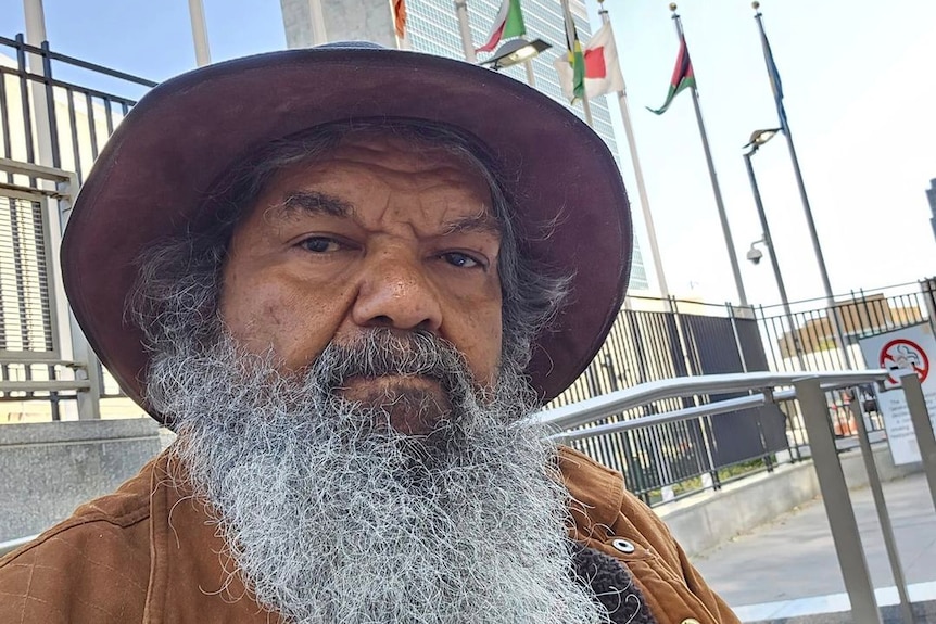 Aboriginl elder with beard and hat in front of the UN headquarters 