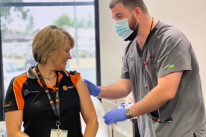 A woman receiving the vaccine from a male health worker