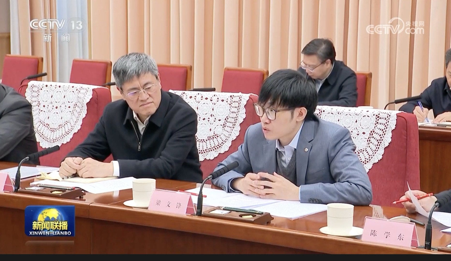 Two men sitting on a table speaking.