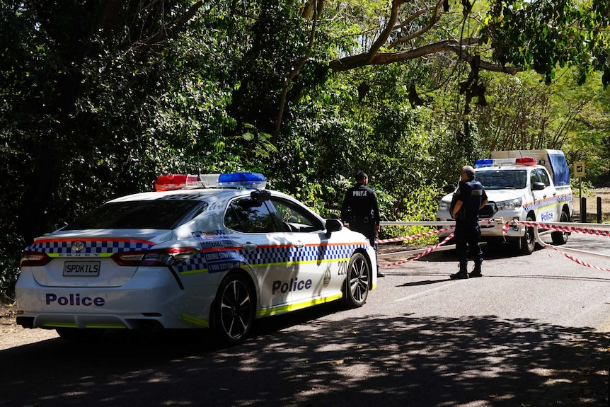 Two NT Police cars and police tape can be seen near the entrance to a walking track near Casuarina Beach.