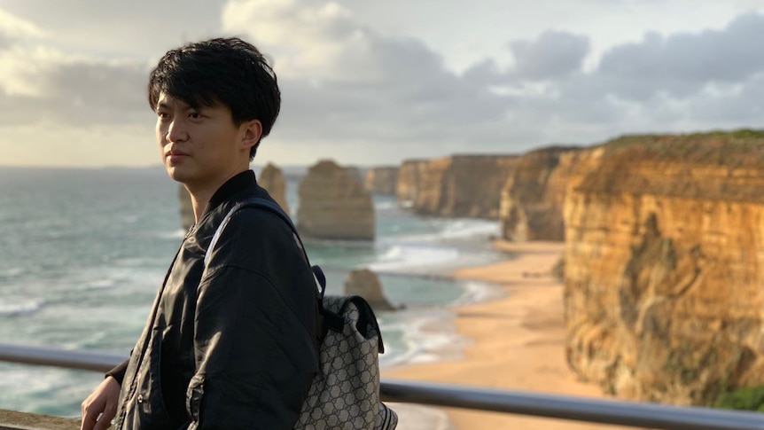 A young Chinese man standing in front of the Twelve Apostles.