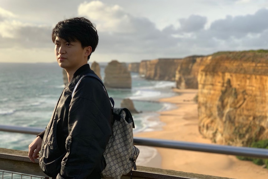 A young Chinese man standing in front of the Twelve Apostles.