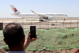 People watch a plane preparing to take off at an airport.