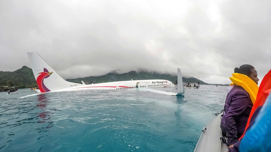 Passengers sit in a rescue boat near the crashed plane