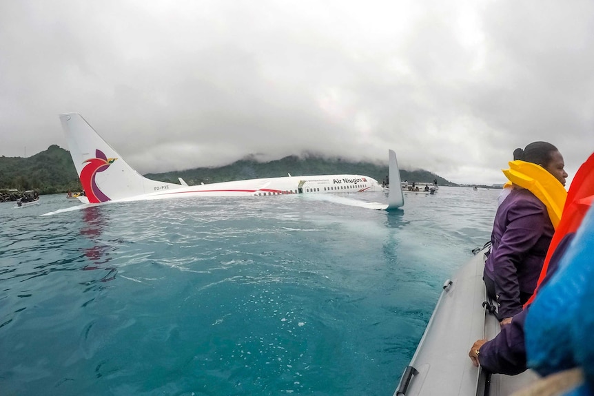 Passengers sit in a rescue boat near the crashed plane