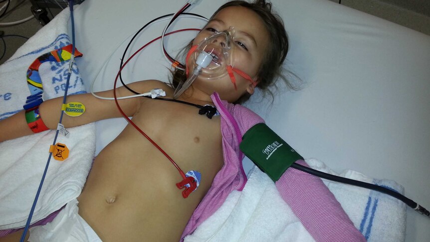 A small girl in hospital with wires and an oxygen mask