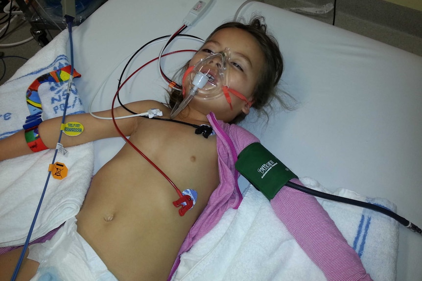 A small girl in hospital with wires and an oxygen mask