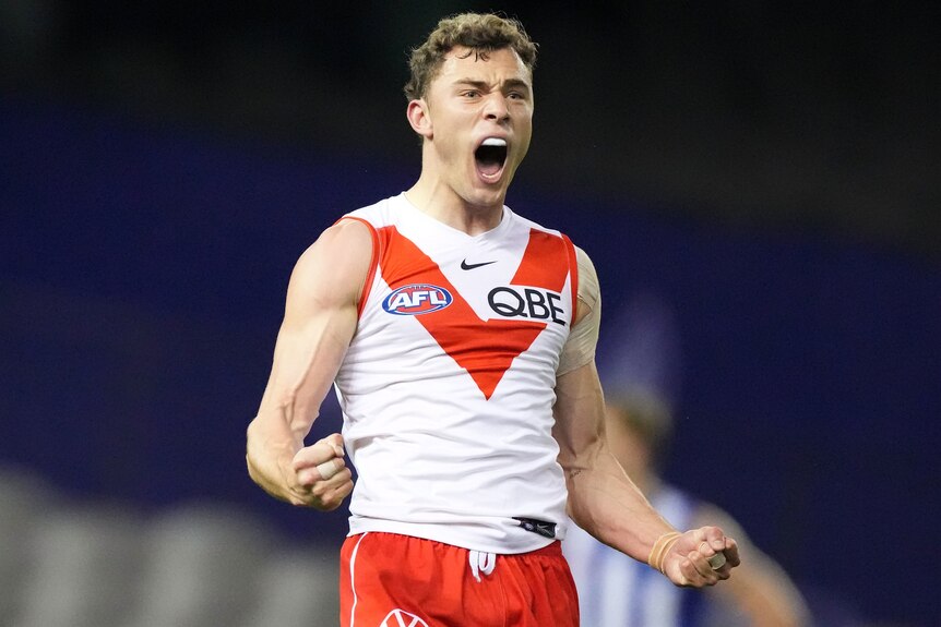 A Sydney Swans AFL player pumps his fists as he celebrates kicking a goal.