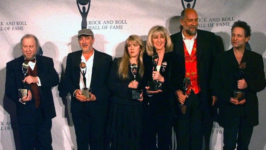 Three women and three men in formal wear line up and hold awards as they pose for a photograph