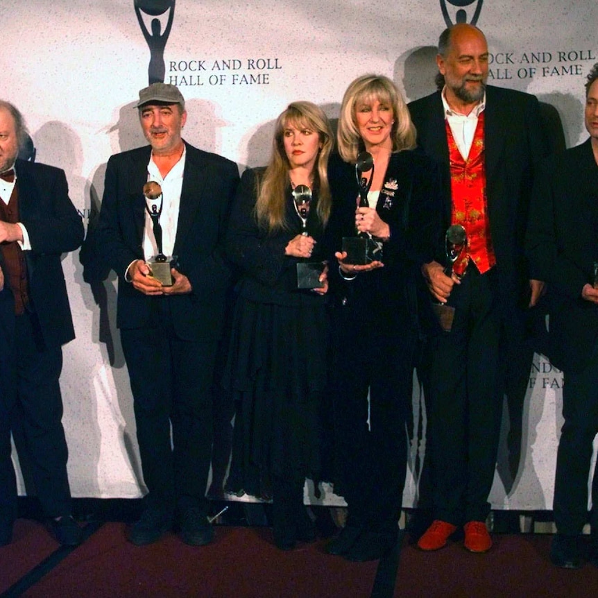 Three women and three men in formal wear line up and hold awards as they pose for a photograph