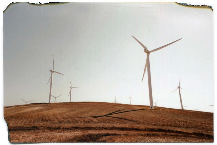 Ten wind turbines on a dry-looking hill.