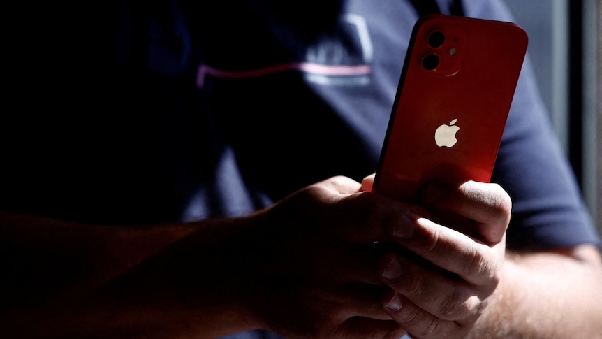 A man poses with an Apple iPhone 12 in a mobile phone store in Nantes, France, September 13, 2023