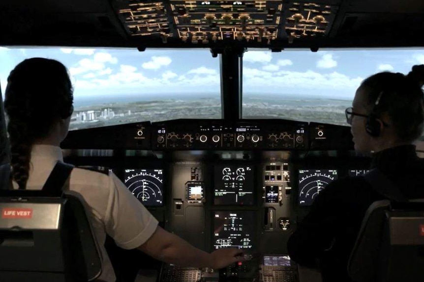 Two female pilots in a flying simulator.