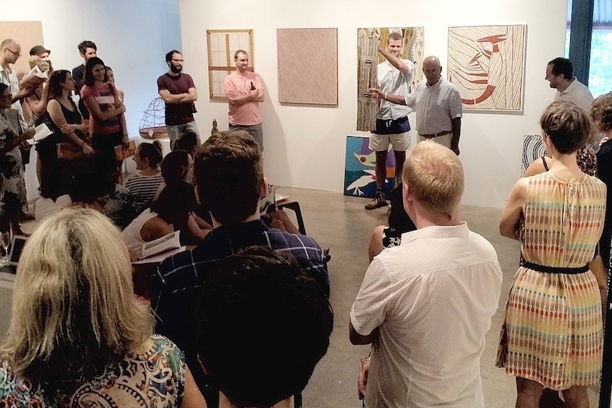 A group of people stand around an auctioneer.