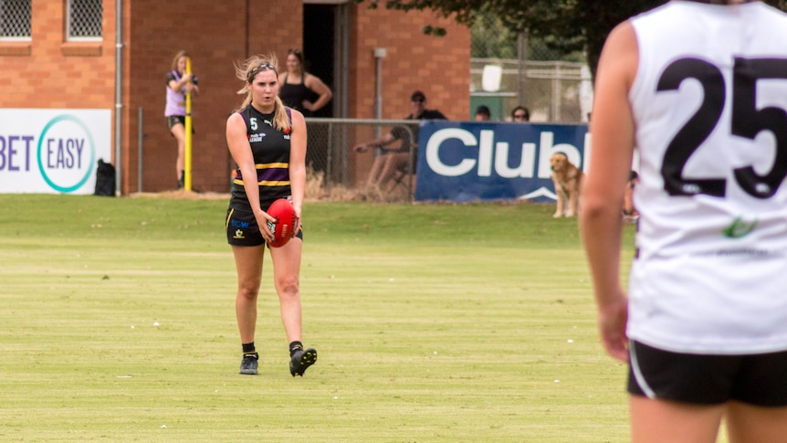 A young woman gets ready to kick an Australian rules football