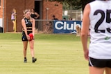 A young woman gets ready to kick an Australian rules football