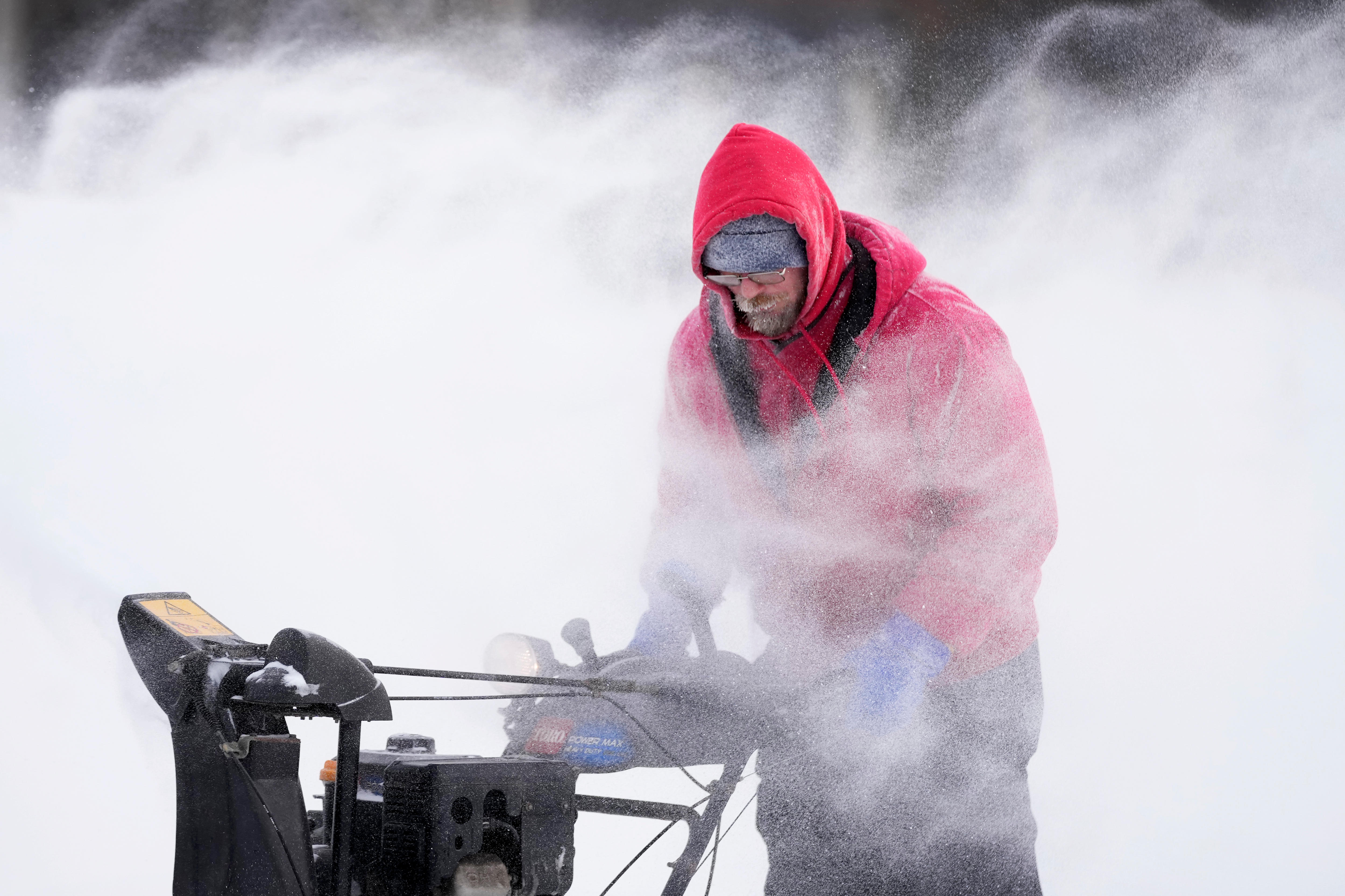 A man clears snow from a downtown ice skating rink.