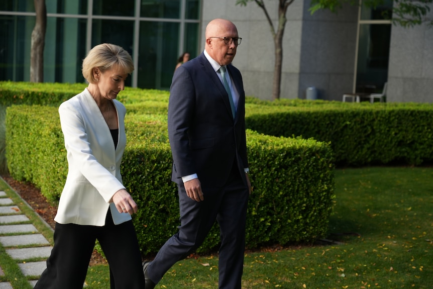 Michaelia Cash and Peter Dutton walking to a press conference in a courtyard at Parliament House