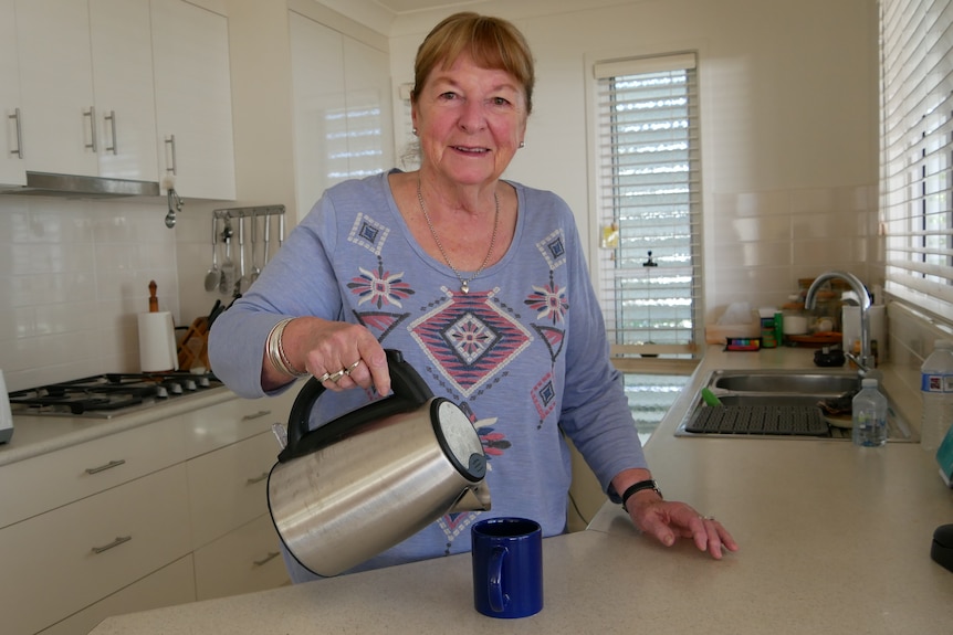 Older woman in the kitchen pouring a cup of tea