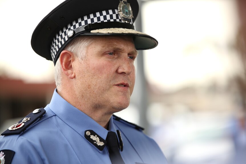 A middle-aged policeman in uniform speaks to the media.