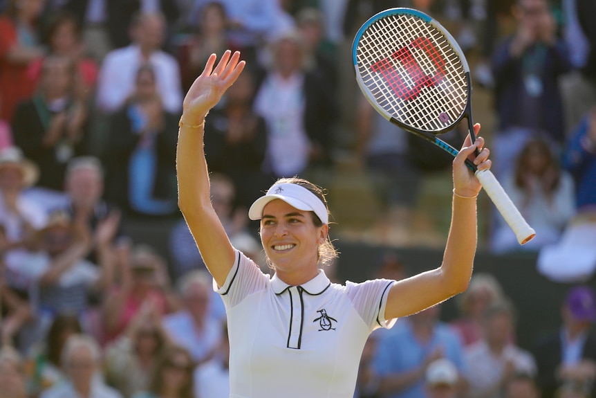 La tenista australiana Ajla Tomljanovic levanta ambas manos, una sosteniendo una raqueta, para agradecer a la multitud de Wimbledon.