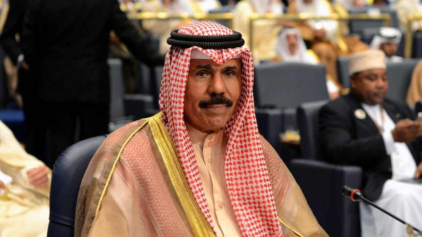 A man wearing traditional Arab red and white head scarf and golden gown