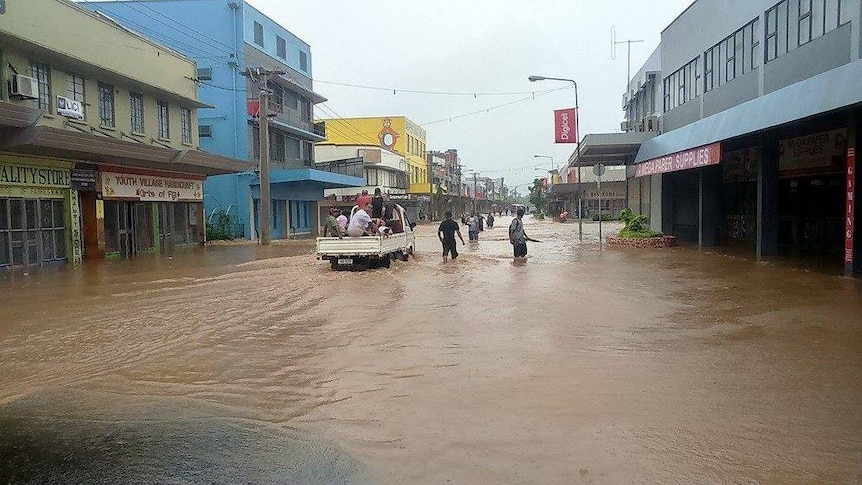 People wade through a flooded road in Nadi.