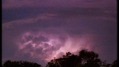 Storm clouds glow purple during lightning strike