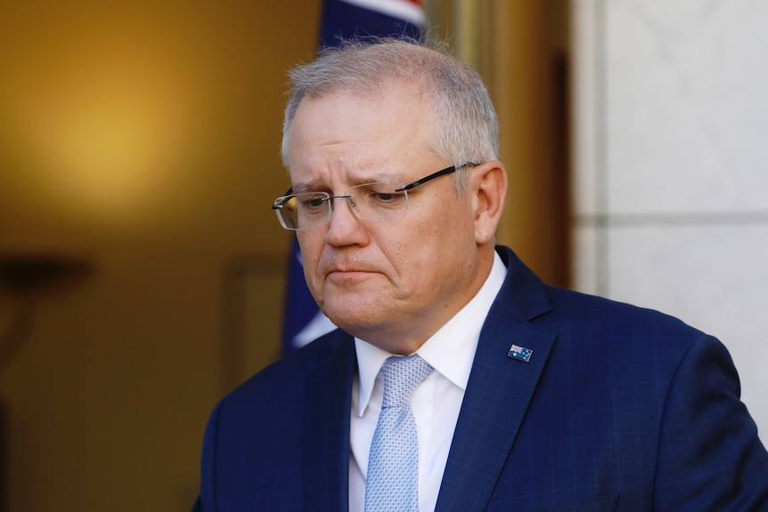 Man with grey hair and glasses looking sad.