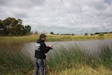 Man casting fishing line into waterway