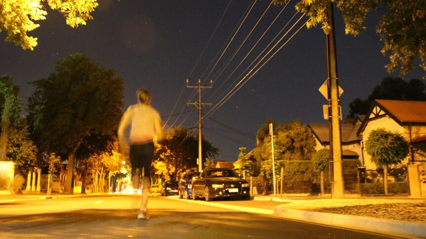 A woman running in the middle of a road at night