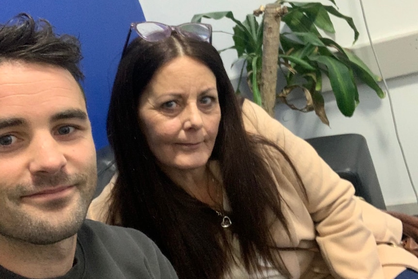 A selfie of Ben Lucas and Mum Sarah in a waiting room with a plant in the background 