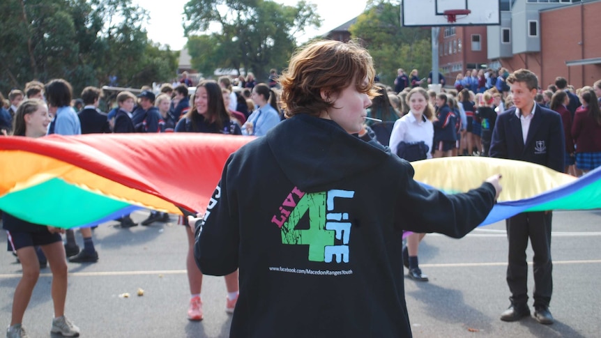 The back of a student wearing a hoodie with Right4Life printed on it with a crowd of students in front of her.