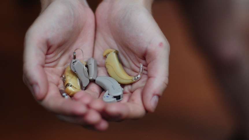 A collection of hearing aids held in composer Rebecca Bracewell's hands.