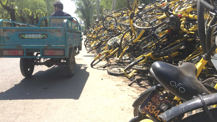 Yellow and black, broken and discarded bicycles pile up on the side of a street in China.