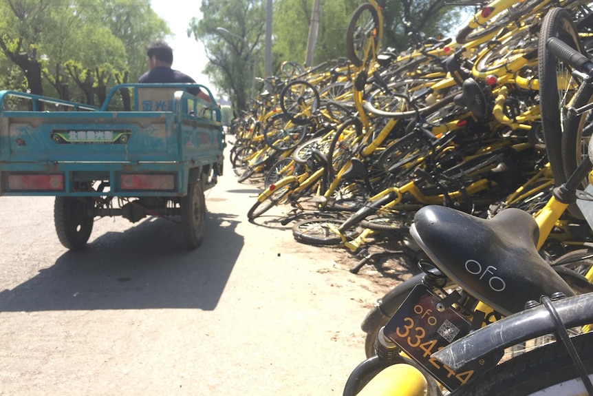 Yellow and black, broken and discarded bicycles pile up on the side of a street in China.