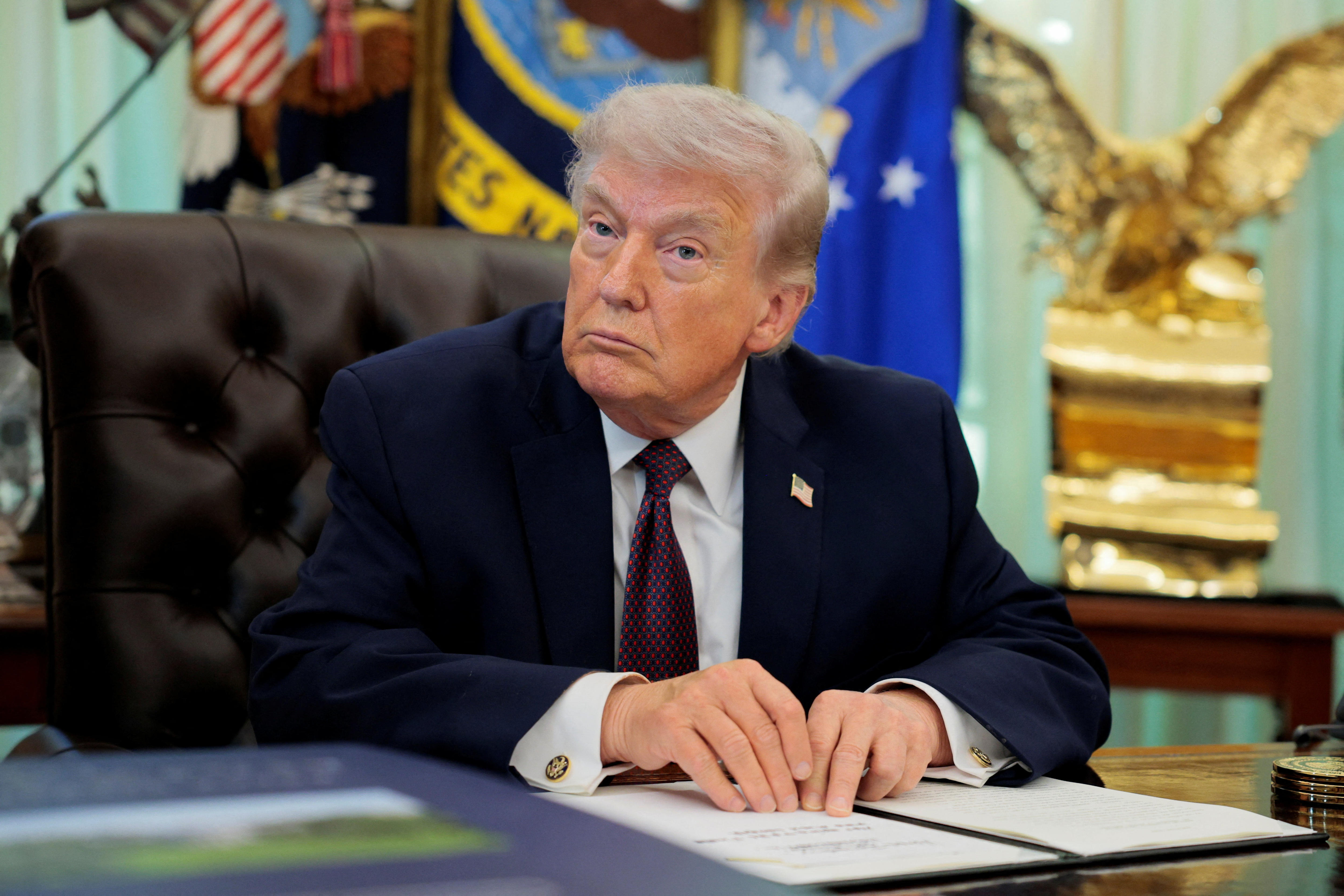 A man in a suit and tie sits at a desk