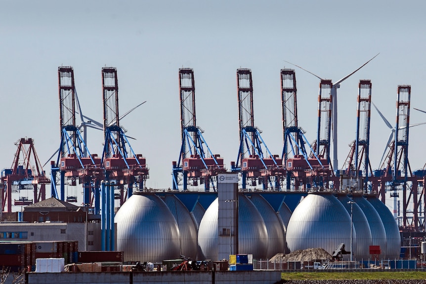 Trois énormes réservoirs d'argent pour la production de biogaz sont représentés dans un port industriel.